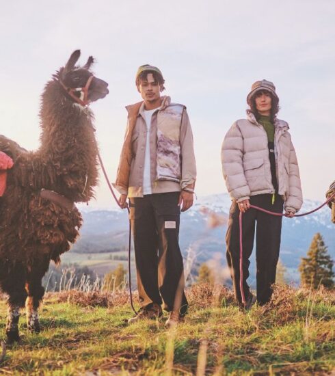 Due persone in abbigliamento Columbia della collezione autunno 2024 accanto a due lama, con uno sfondo di montagne e natura al tramonto.